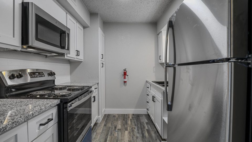 kitchen with stainless steel appliances and white cabinets at The Flats on Handley