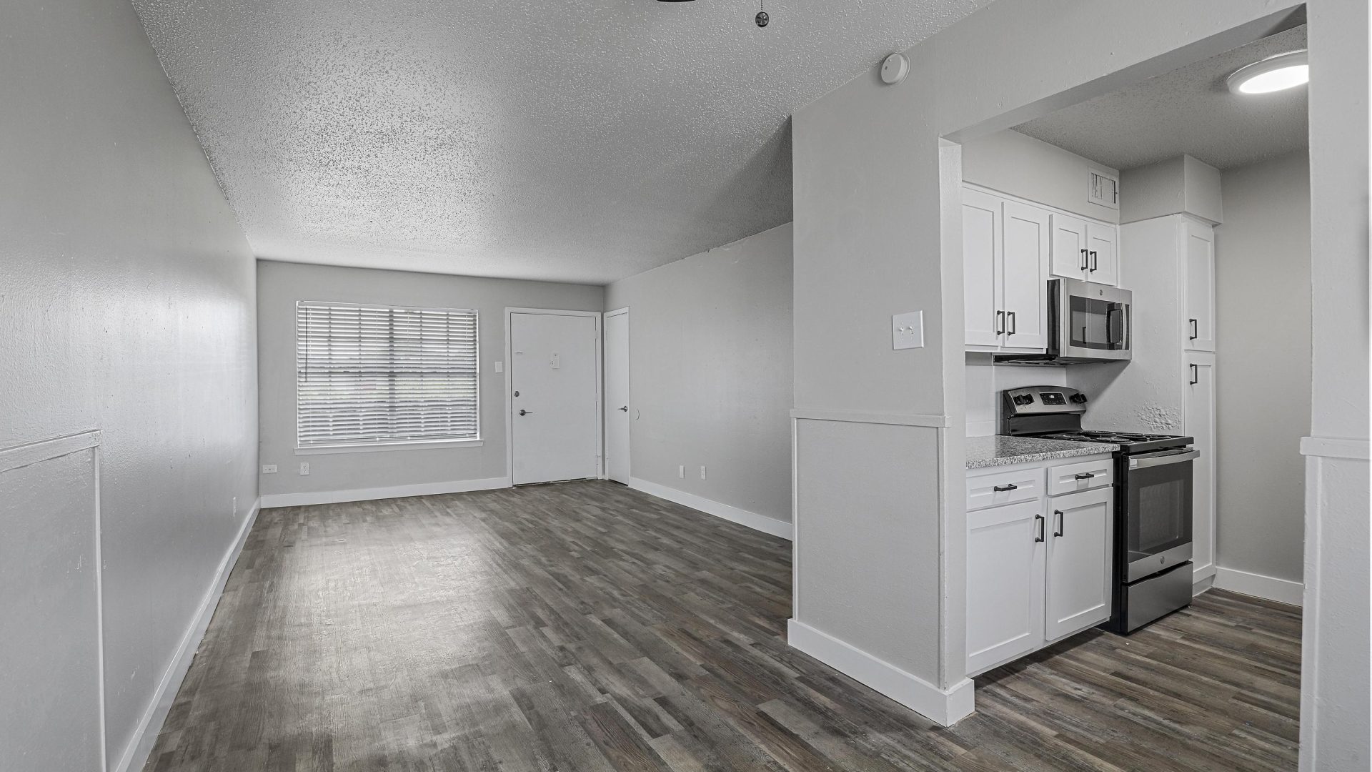 an empty room with white walls and hardwood floors at The Flats on Handley