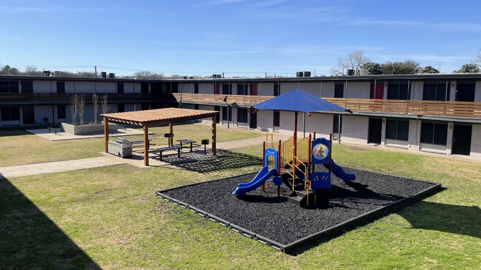 a playground area with a slide and swings at The Flats on Handley